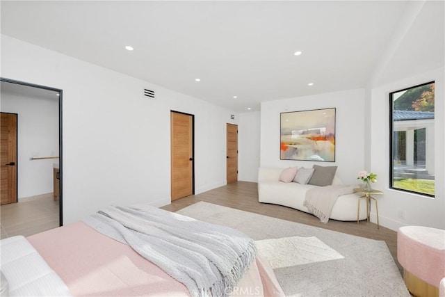 bedroom with baseboards, light wood finished floors, visible vents, and recessed lighting