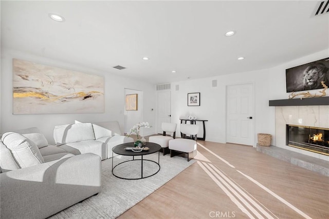 living room featuring a high end fireplace, visible vents, wood finished floors, and recessed lighting