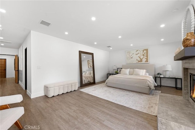 bedroom featuring a fireplace with flush hearth, recessed lighting, visible vents, and wood finished floors