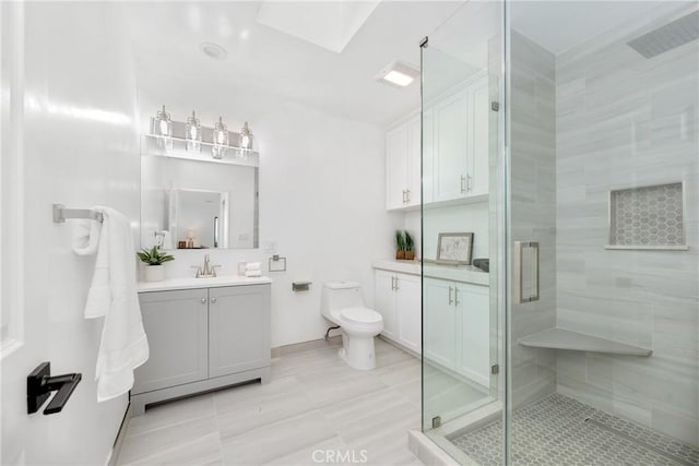 bathroom with tile patterned flooring, toilet, a skylight, vanity, and a stall shower