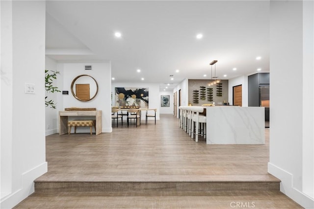 interior space featuring recessed lighting, indoor bar, light wood-style flooring, and baseboards