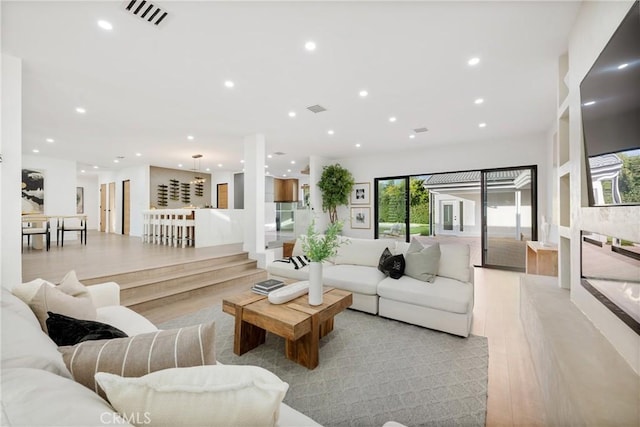 sunken living room with light wood-style floors, visible vents, and recessed lighting