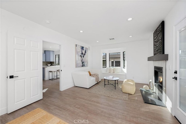 living area with recessed lighting, a fireplace, baseboards, and wood finished floors