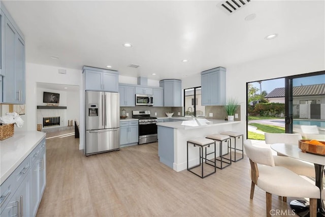 kitchen featuring stainless steel appliances, light countertops, visible vents, light wood-type flooring, and a peninsula