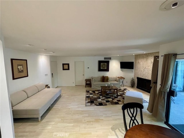 living room with visible vents, a fireplace, and light wood-style flooring