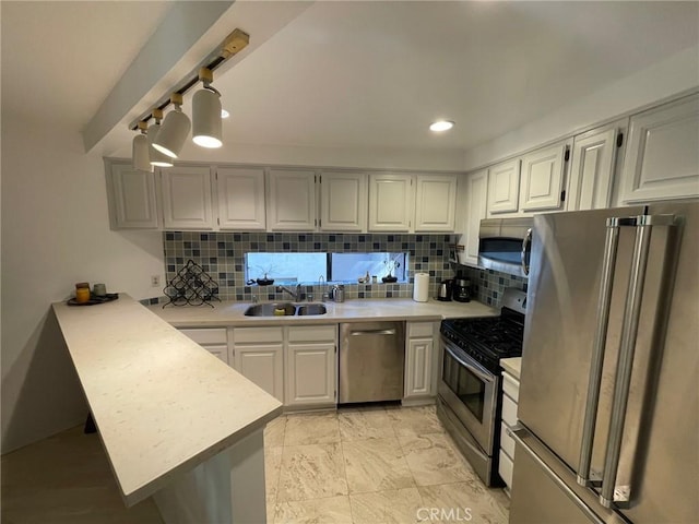 kitchen with stainless steel appliances, a peninsula, a sink, and light countertops