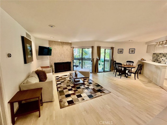 living room with a large fireplace, light wood-style flooring, visible vents, and recessed lighting