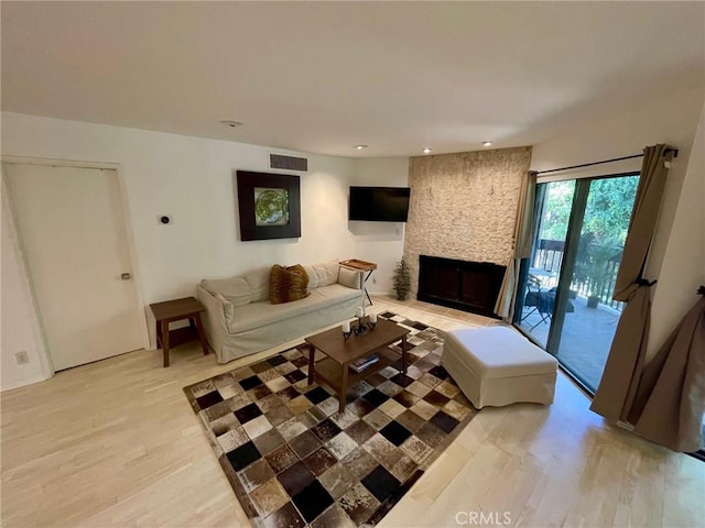 living area featuring light wood-style floors, recessed lighting, a large fireplace, and visible vents