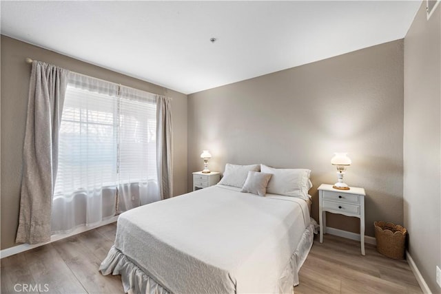 bedroom with light wood finished floors and baseboards