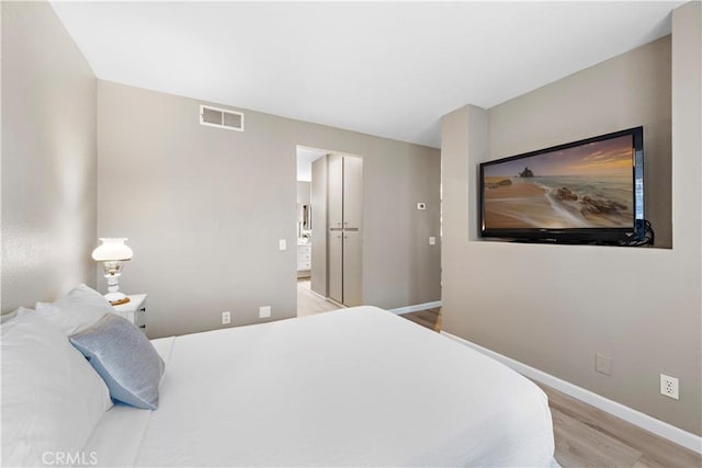 bedroom with light wood-style floors, visible vents, and baseboards