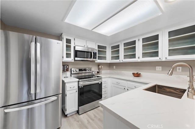 kitchen with white cabinets, glass insert cabinets, stainless steel appliances, and a sink