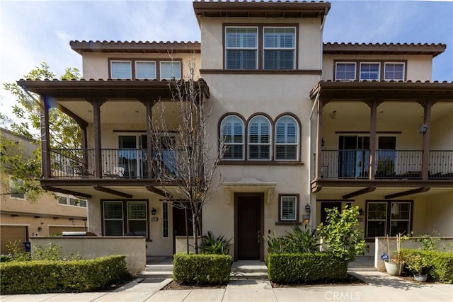 view of front facade with a balcony and stucco siding