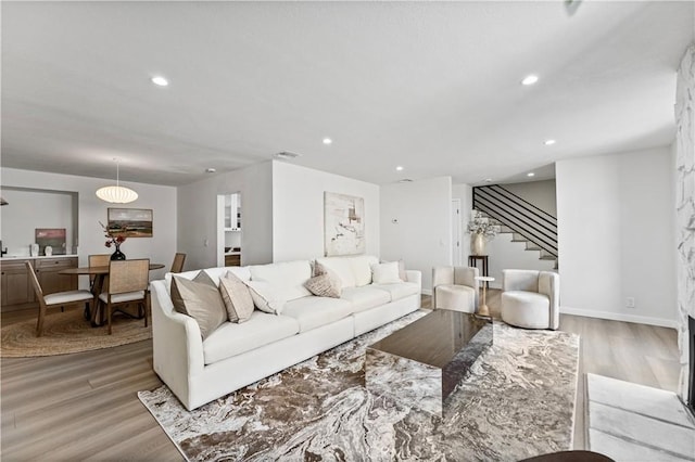 living area with visible vents, baseboards, stairway, light wood-type flooring, and recessed lighting