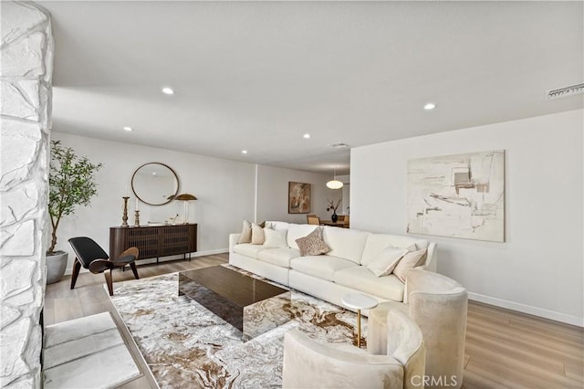 living area featuring light wood-style floors, recessed lighting, visible vents, and baseboards