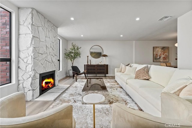 living room with light wood-style floors, a fireplace, visible vents, and recessed lighting