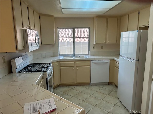 kitchen featuring white appliances, a sink, and tile countertops