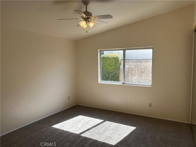 empty room with dark carpet, vaulted ceiling, baseboards, and ceiling fan