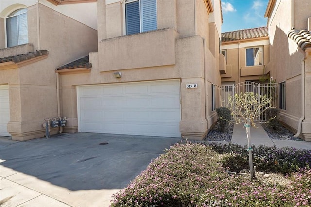 view of front of property with driveway, an attached garage, a tile roof, and stucco siding