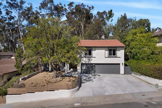 view of front of home with a garage, driveway, a tiled roof, and stucco siding