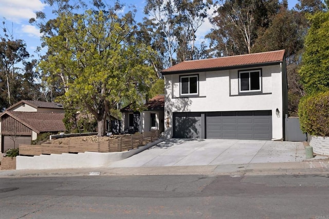 view of front of home with an attached garage, driveway, a tile roof, and stucco siding