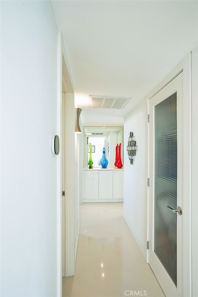 corridor featuring visible vents, baseboards, and tile patterned floors