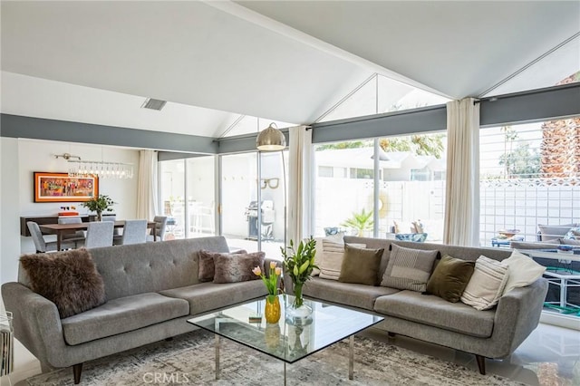 sunroom / solarium featuring visible vents, vaulted ceiling, a wealth of natural light, and a chandelier