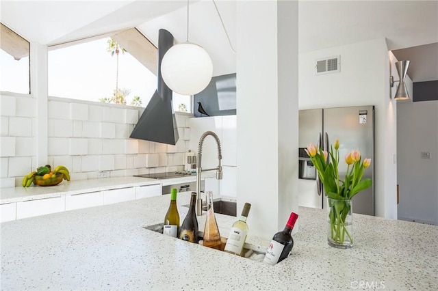 kitchen with stainless steel refrigerator with ice dispenser, black electric stovetop, visible vents, backsplash, and light stone countertops