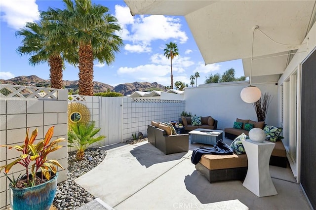 view of patio / terrace with fence, a mountain view, and an outdoor living space with a fire pit