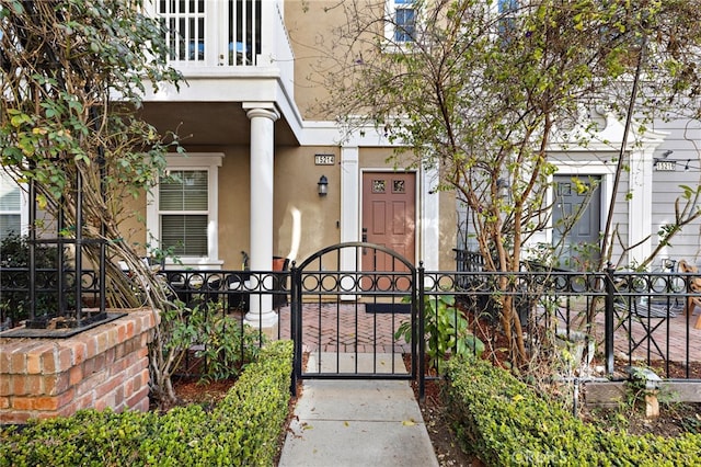 property entrance with a gate, fence, and stucco siding