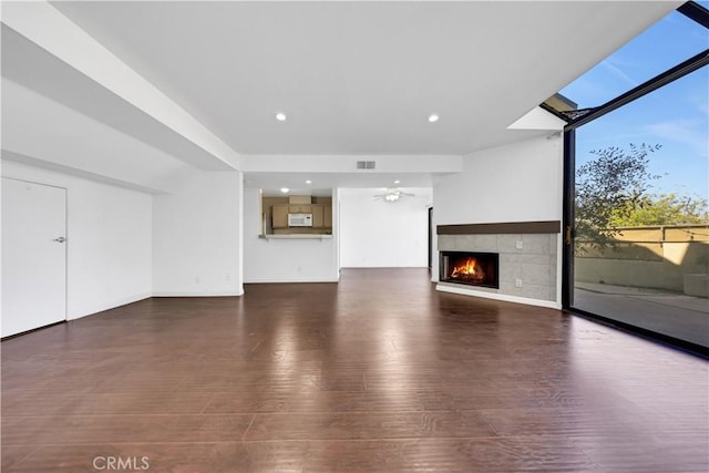 unfurnished living room featuring recessed lighting, a skylight, a fireplace, visible vents, and dark wood finished floors