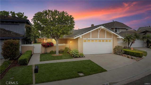 view of front facade featuring an attached garage, driveway, a tiled roof, a lawn, and stucco siding