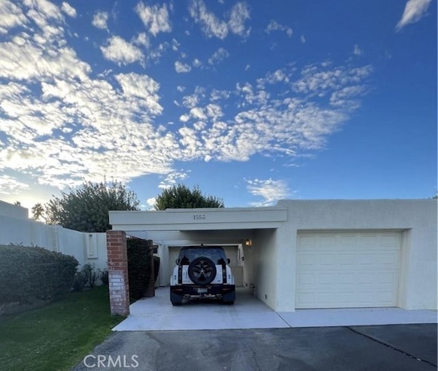 garage featuring concrete driveway and fence