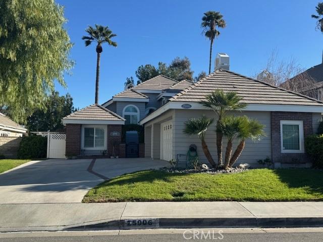 view of front of house featuring an attached garage, a front lawn, concrete driveway, and a tiled roof