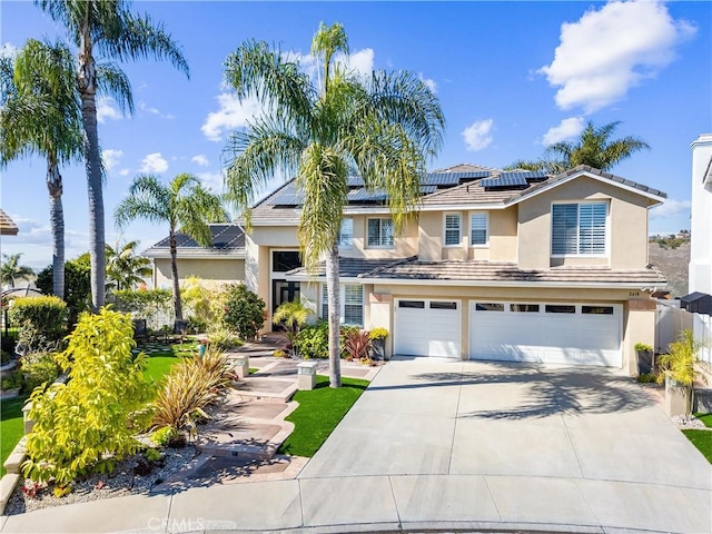 traditional-style house with stucco siding, solar panels, concrete driveway, an attached garage, and a tiled roof