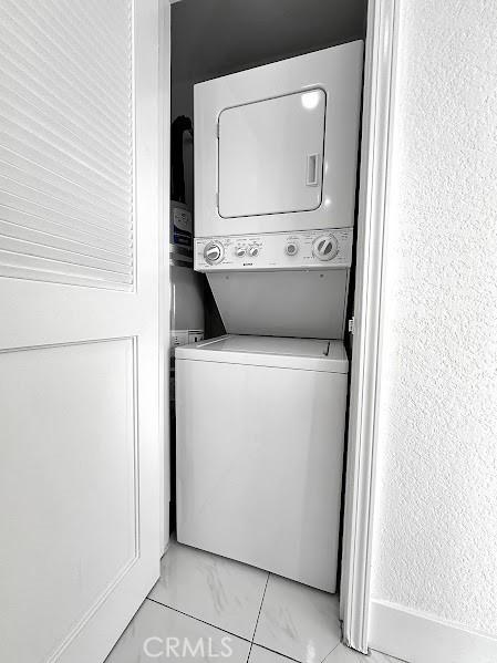clothes washing area with stacked washer and clothes dryer and laundry area