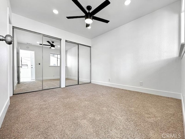 unfurnished bedroom featuring carpet, two closets, recessed lighting, and baseboards