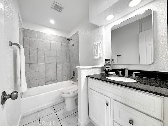 bathroom with vanity, bathing tub / shower combination, toilet, visible vents, and a textured wall