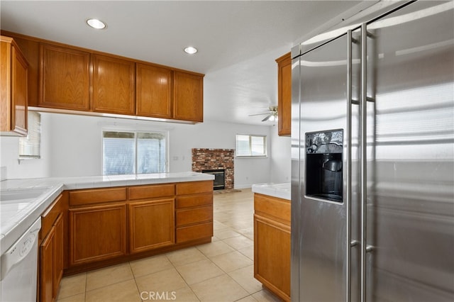 kitchen with tile countertops, brown cabinetry, white dishwasher, high quality fridge, and ceiling fan