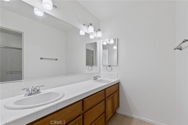 full bathroom with double vanity, tile patterned flooring, baseboards, and a sink