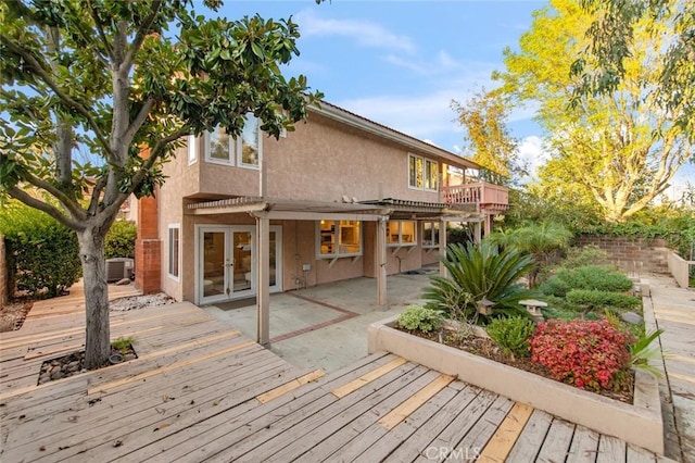 back of house featuring french doors, stucco siding, a patio area, a pergola, and a wooden deck