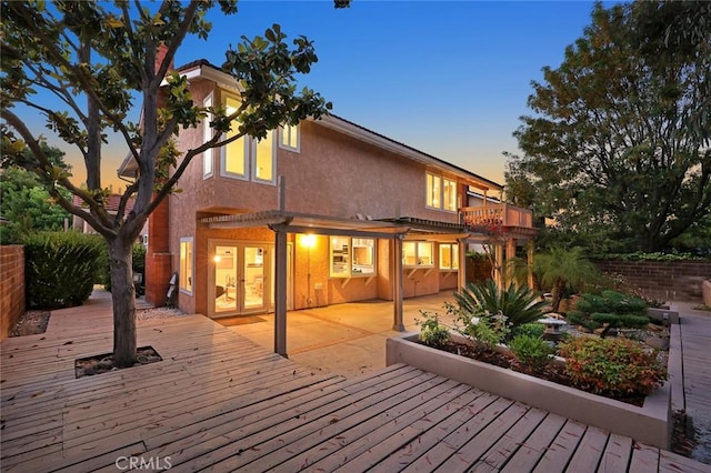 rear view of house with a patio, a balcony, a wooden deck, and stucco siding