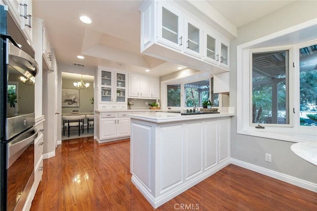 kitchen with glass insert cabinets, light countertops, a chandelier, and white cabinets