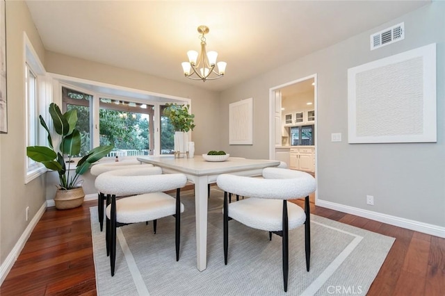 dining room with dark wood-style floors, baseboards, visible vents, and a chandelier