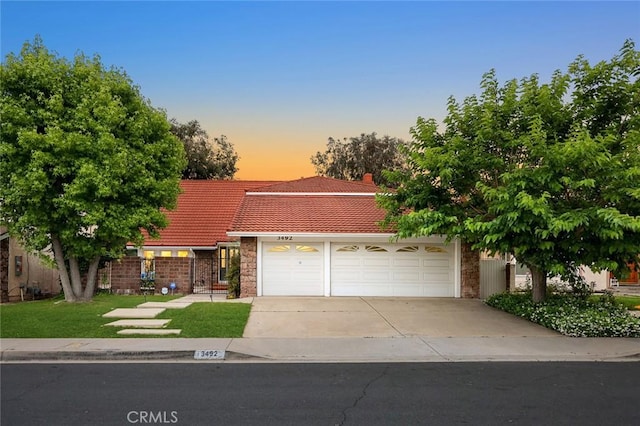 view of front of house with concrete driveway, a tile roof, and an attached garage