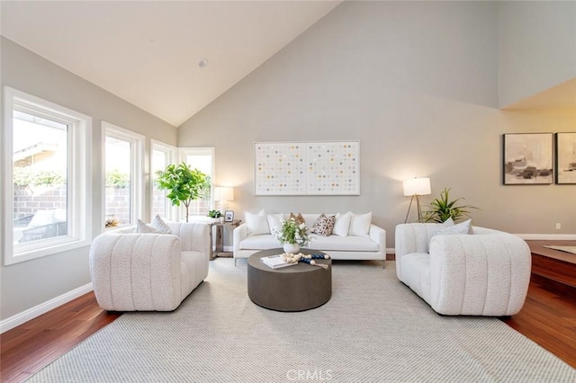 living room with high vaulted ceiling, baseboards, and wood finished floors