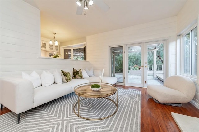 living area with ceiling fan, french doors, wood finished floors, and wooden walls