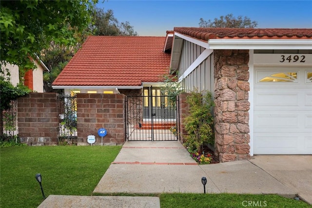 view of front of home featuring stone siding, a tile roof, a gate, and fence