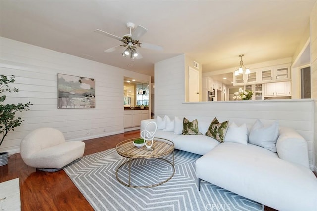 living area featuring visible vents, wood finished floors, and ceiling fan with notable chandelier