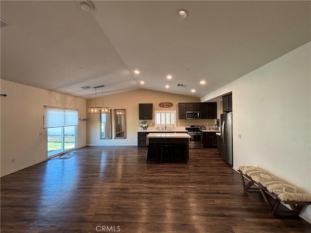 kitchen with lofted ceiling, a kitchen island, appliances with stainless steel finishes, hanging light fixtures, and light countertops