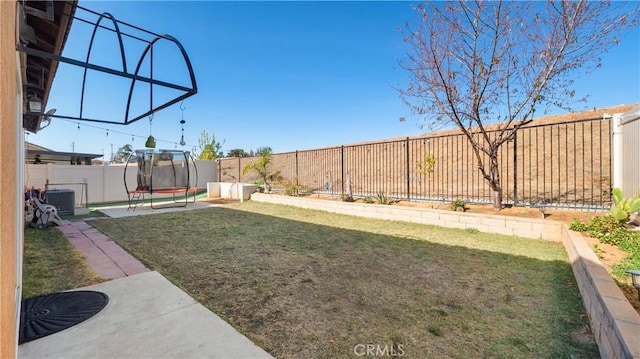 view of yard featuring a trampoline, cooling unit, and a fenced backyard